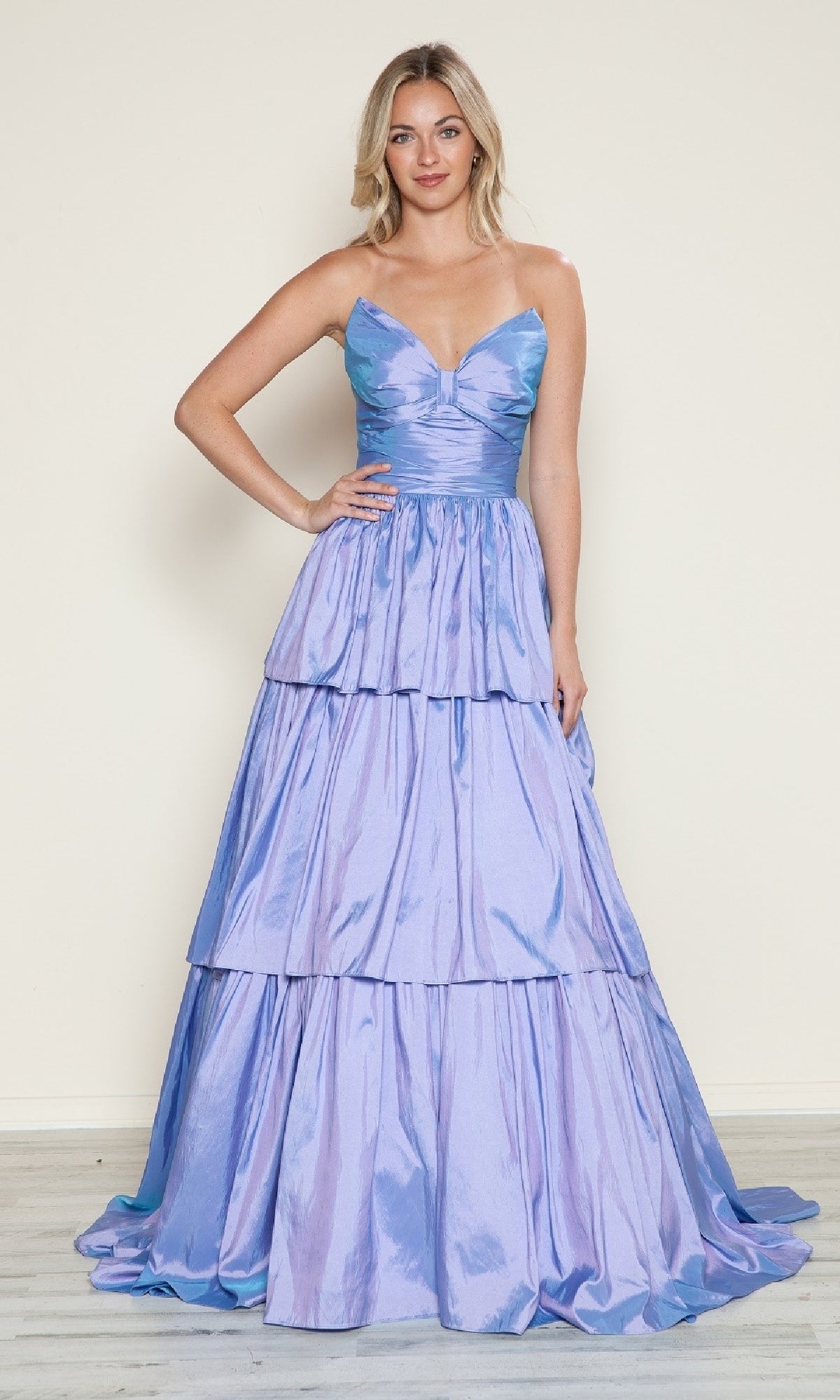 A woman stands against a plain background, wearing the Poly USA 9694 long prom dress in shiny light purple, featuring a fitted bodice, spaghetti straps, and tiered A-line layers.